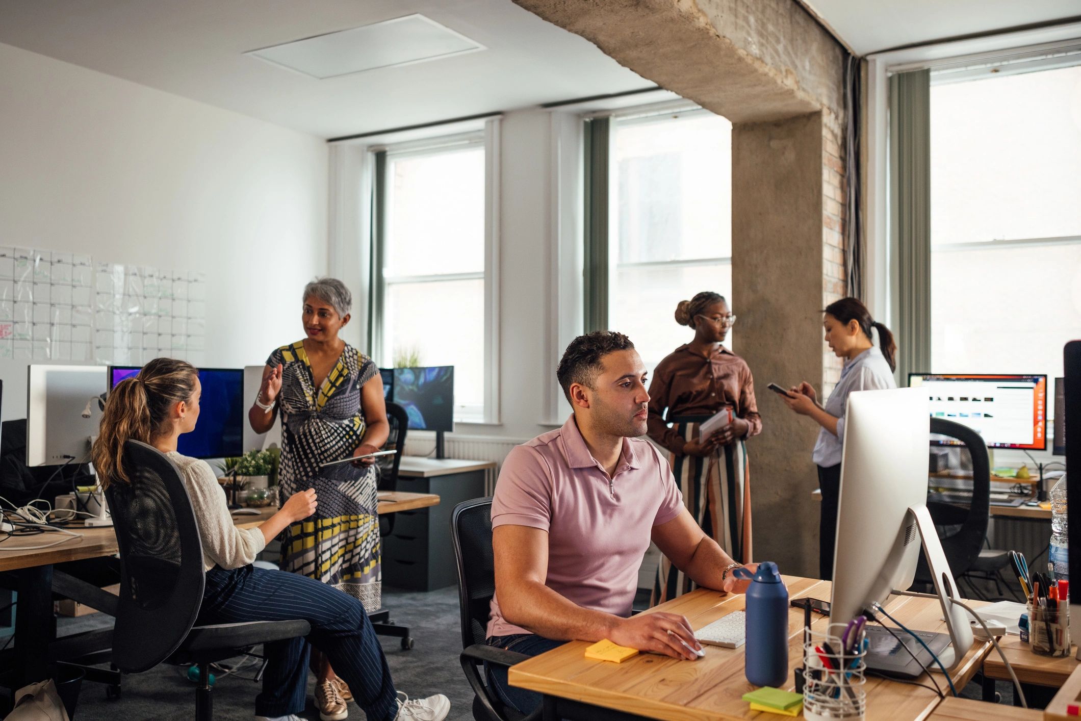 Office professional working while team collaborates nearby